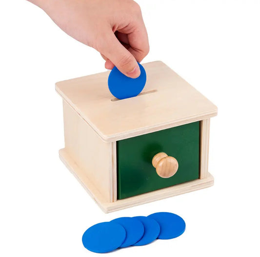 Montessori fa érmébedobó doboz fiókkal és kék korongokkal.